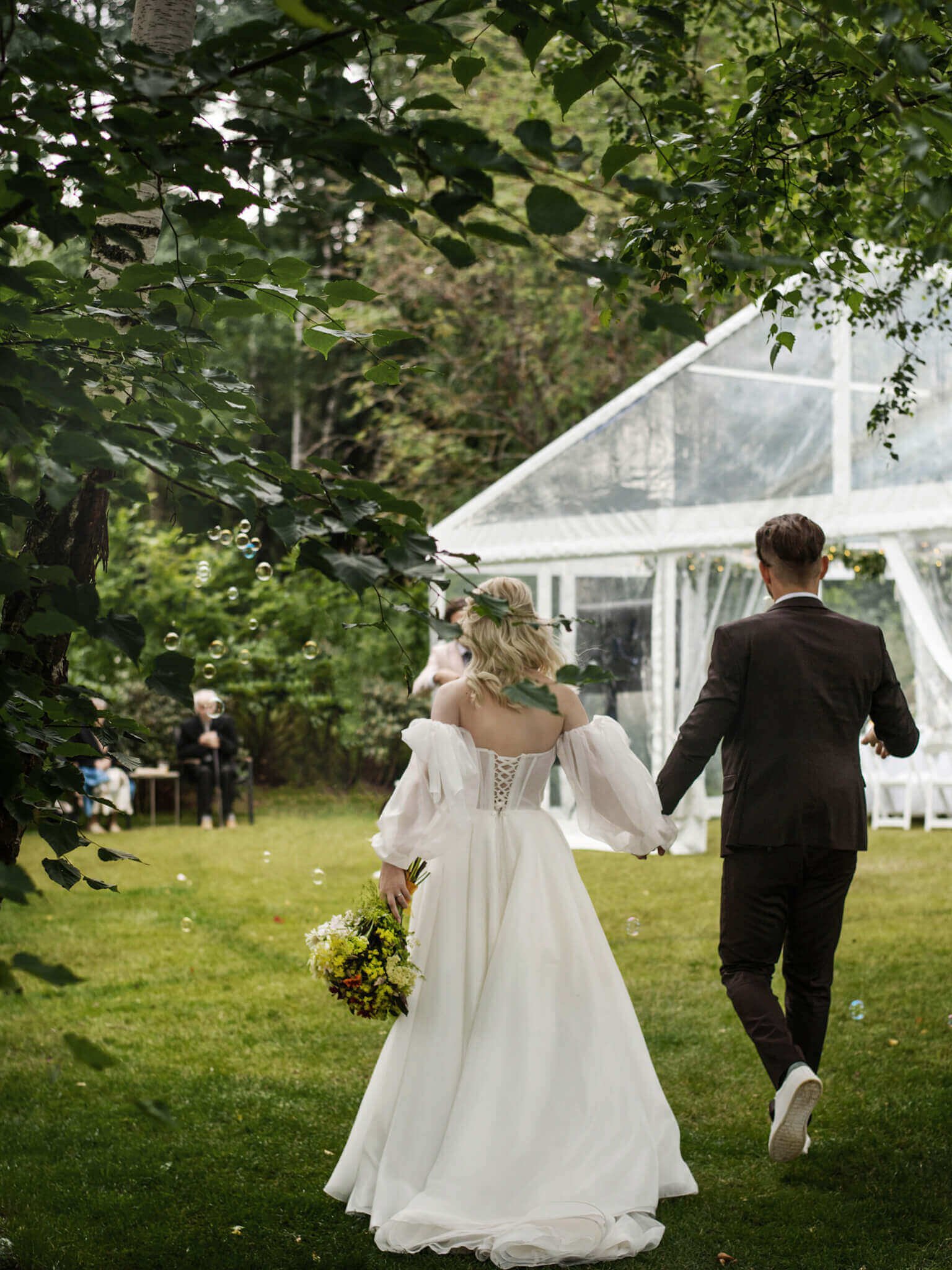 Skaidri paviljono palapinė su medinėmis grindimis ir apvaliais stalais